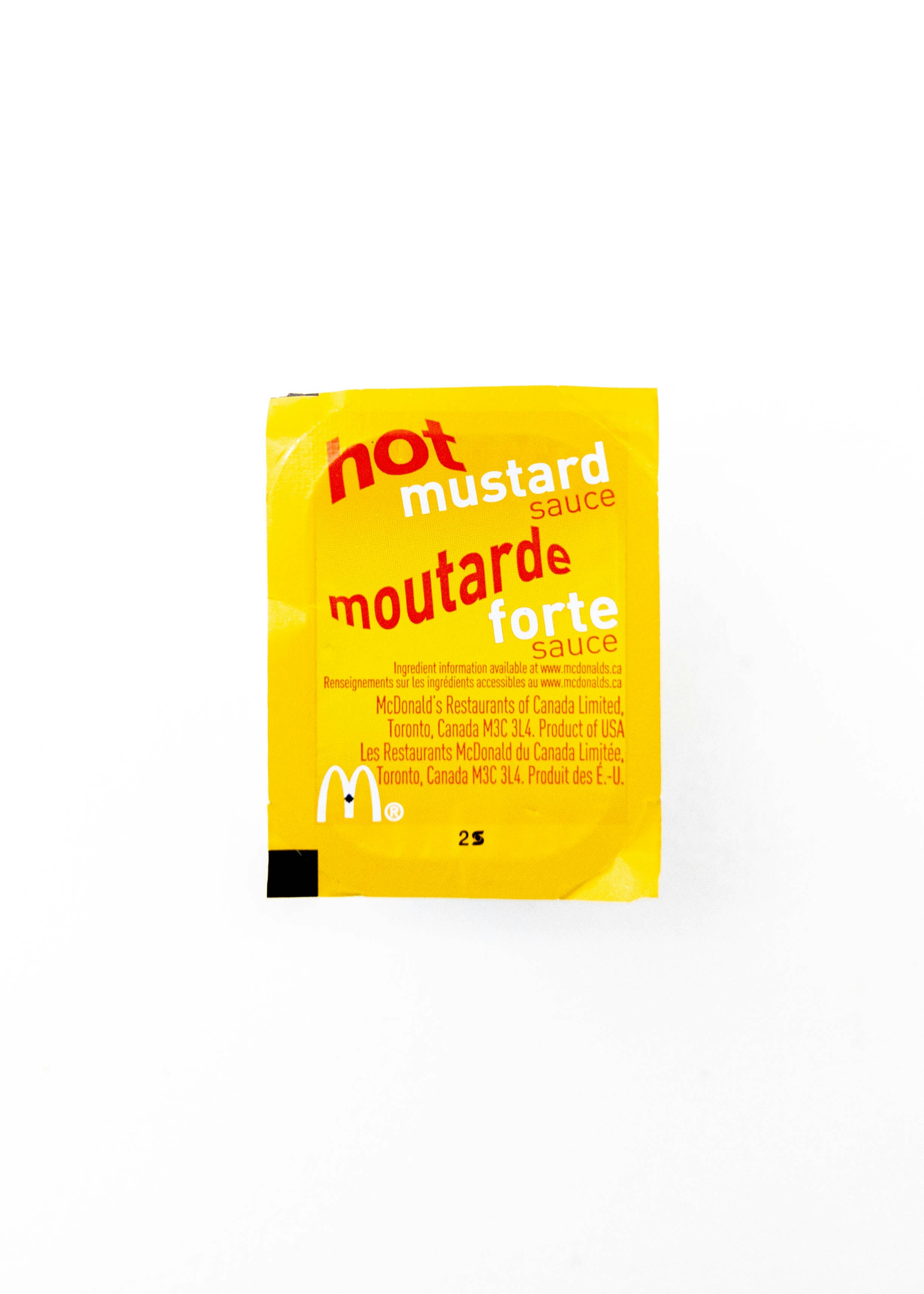 a packet of mustard sitting on top of a white table